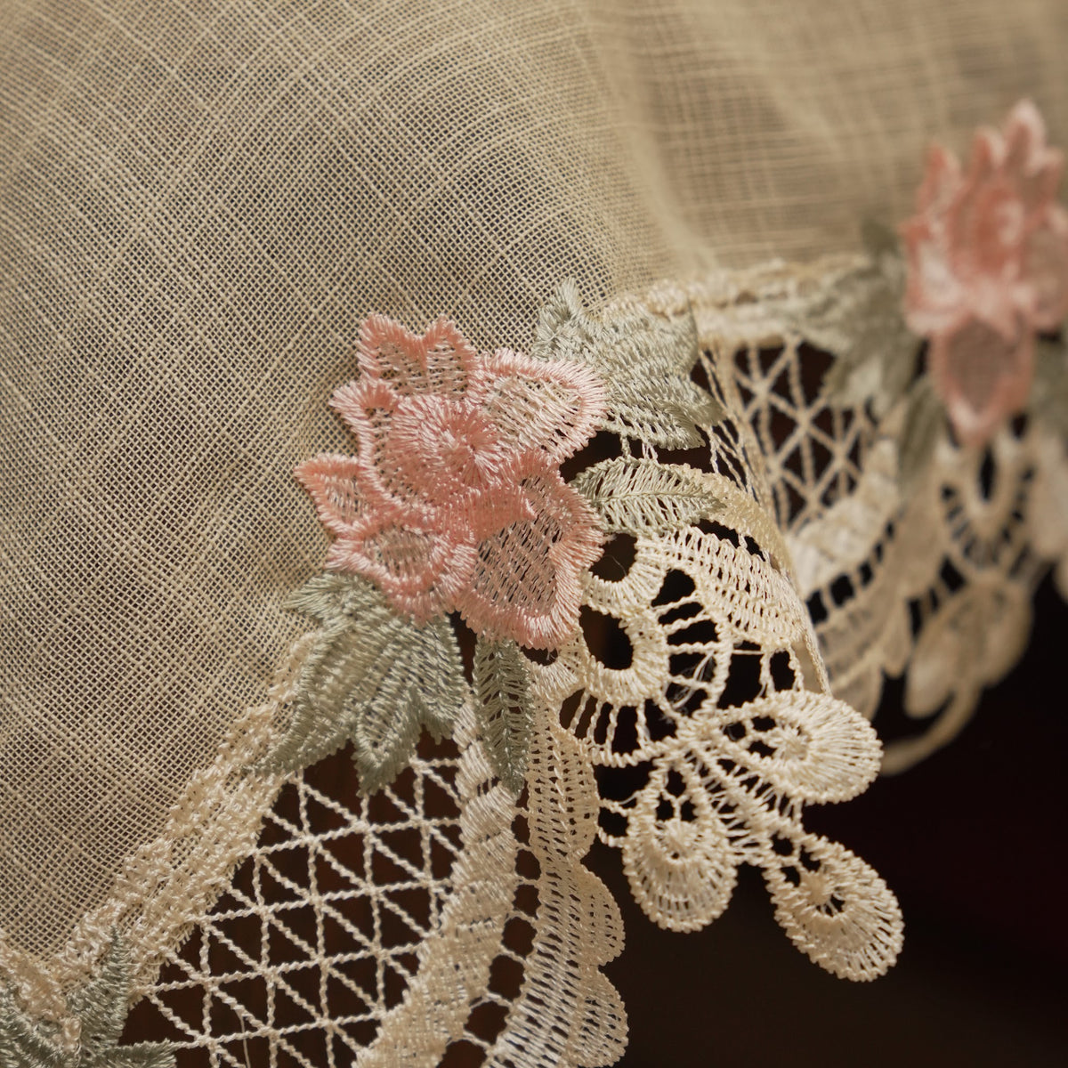 Close-up of the scalloped lace edge with pink rose embroidery
