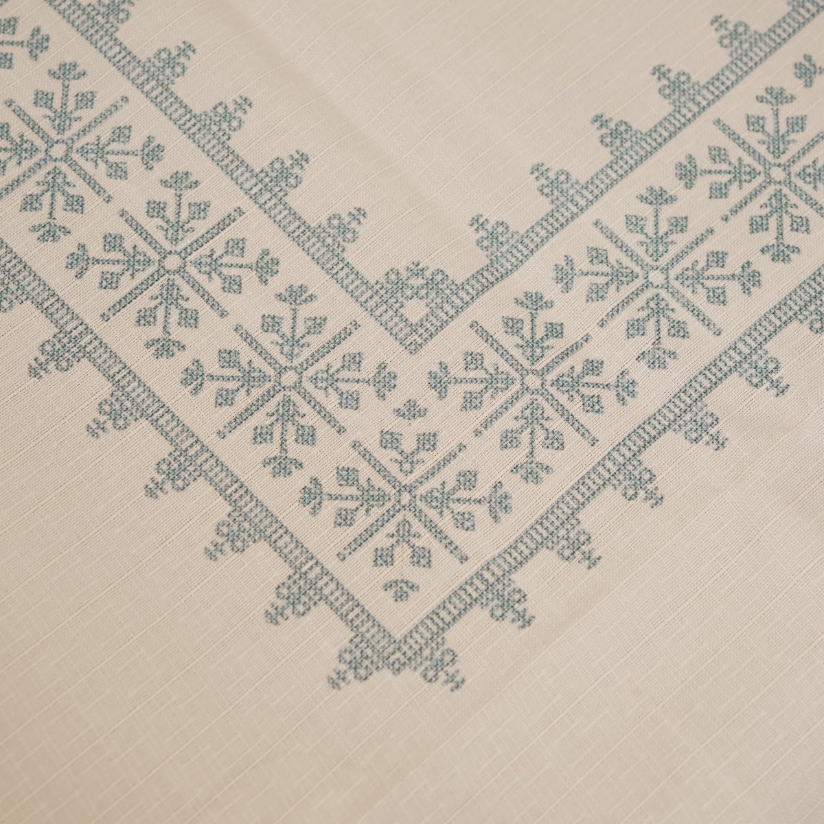 Close-up of the teal blue cross-stitch pattern