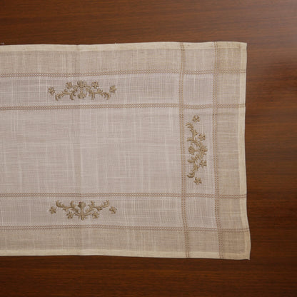 Linen table runner laid flat showing olive cross-stitch sprigs