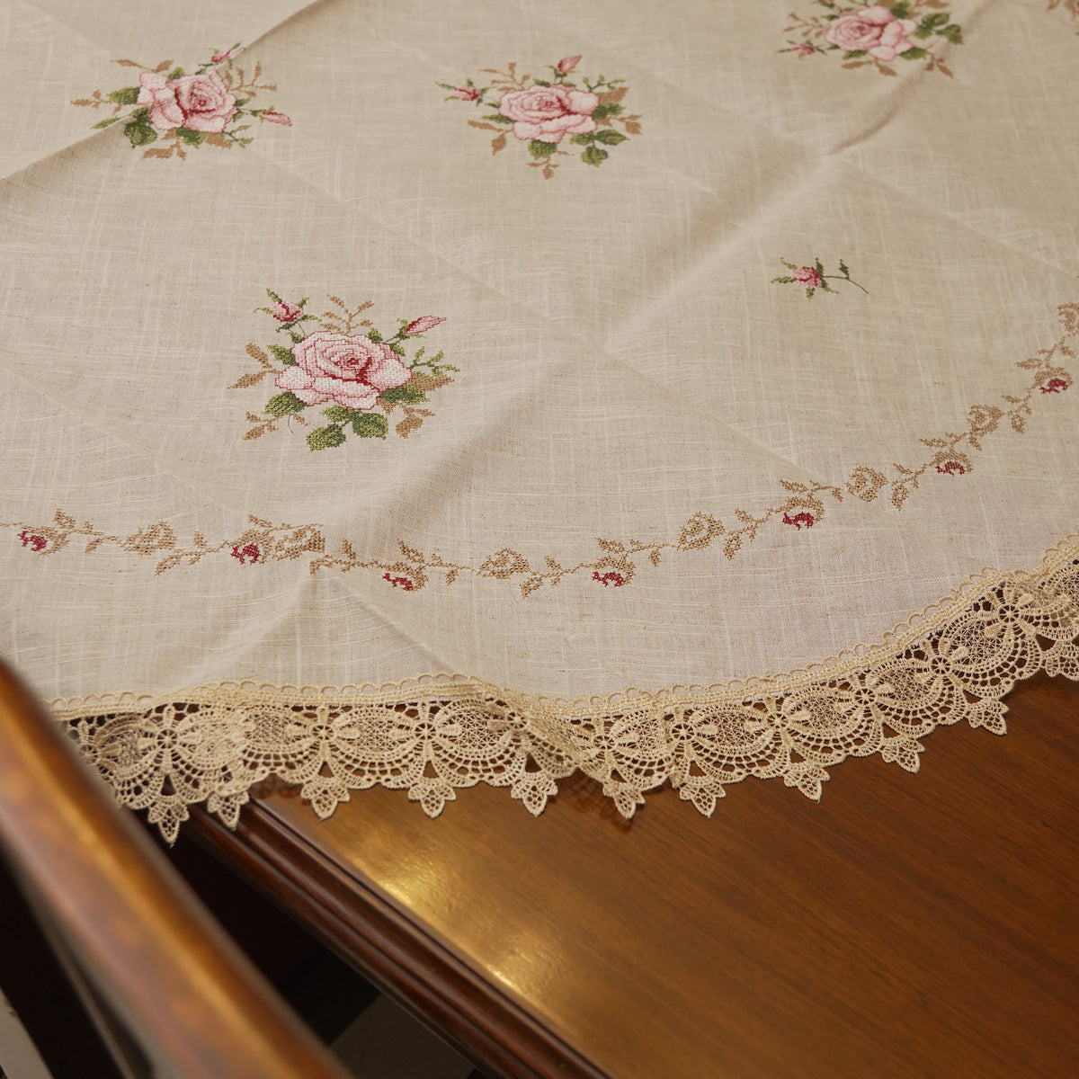 Edge of the round table sheet with pink roses and lace trim