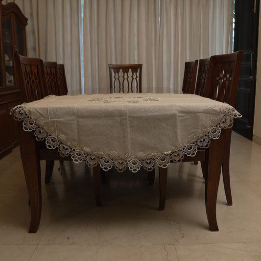 Natural linen round table sheet with lace border on a dining table