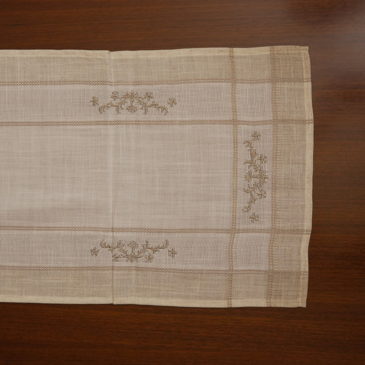 Linen table runner laid flat showing cross-stitch sprigs