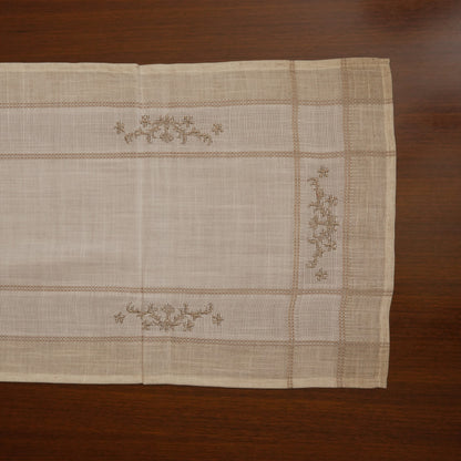 Linen table runner laid flat showing cross-stitch sprigs